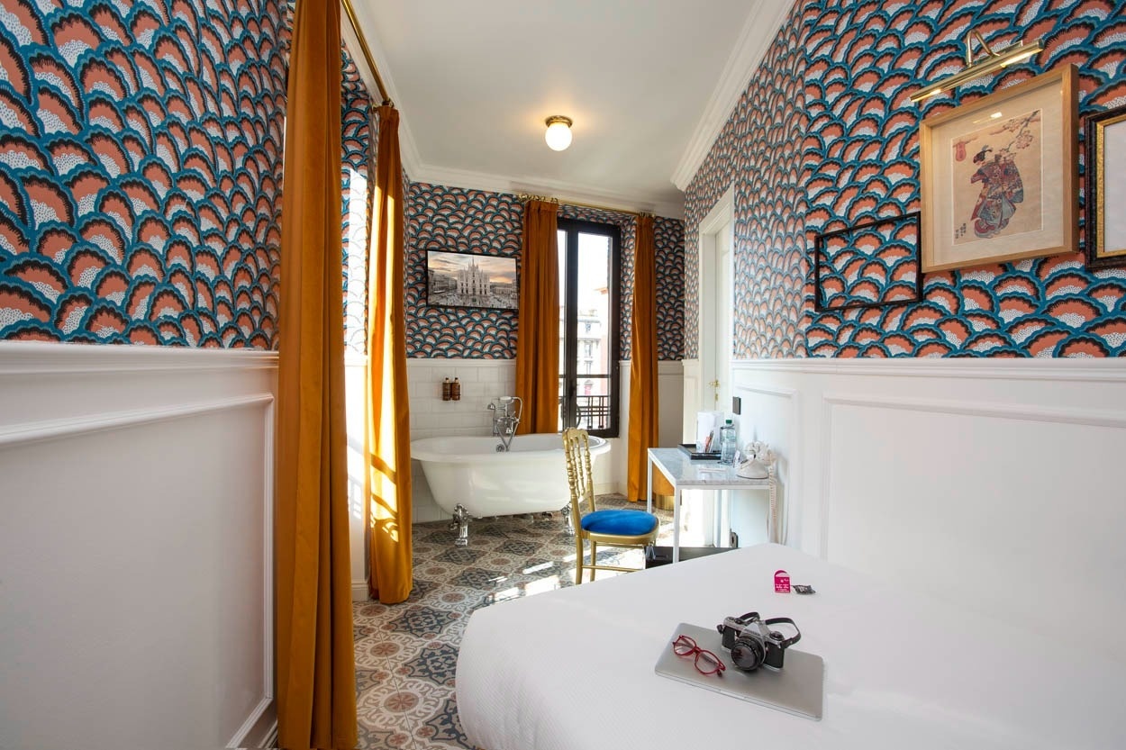 Elegantes Hotelzimmer in Mailand: Freistehende Badewanne, Vintage-Tapete und Blick auf die Stadt. Ideal für Ihren Aufenthalt im Casual Eclettico Milano, nahe dem Bahnhof Centrale.