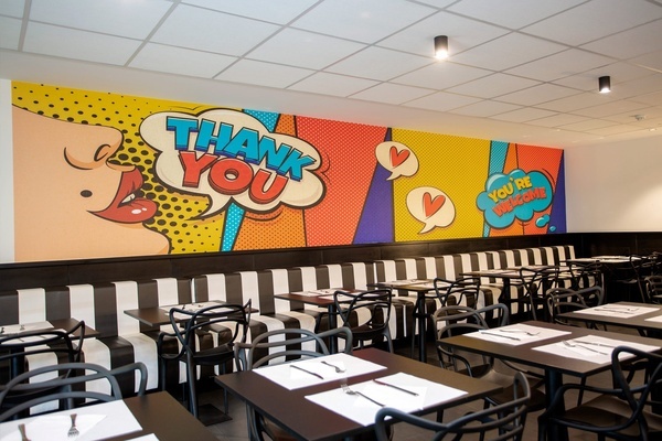 un restaurante con mesas y sillas y un mural que dice 