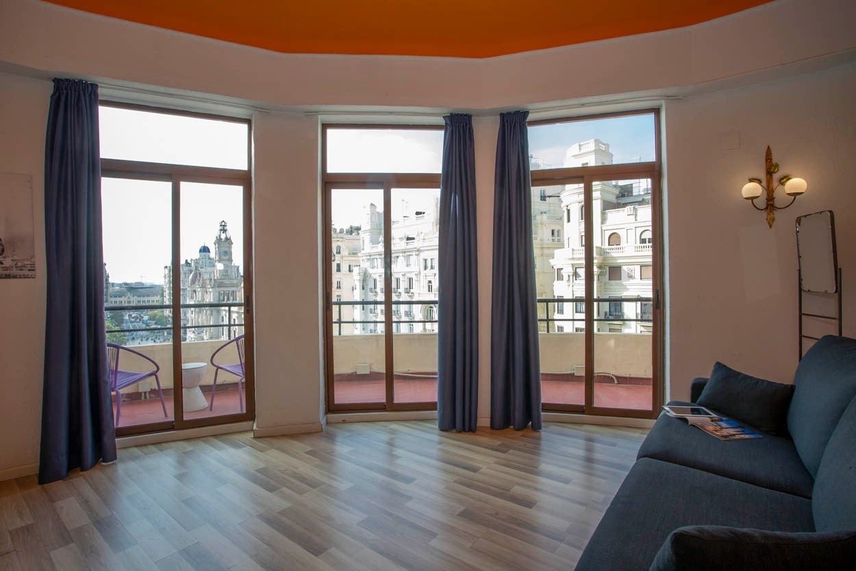 Habitación luminosa con vistas a la ciudad, terraza y sofá cómodo. Casual Vintage Valencia - Hotel céntrico junto al Ayuntamiento.