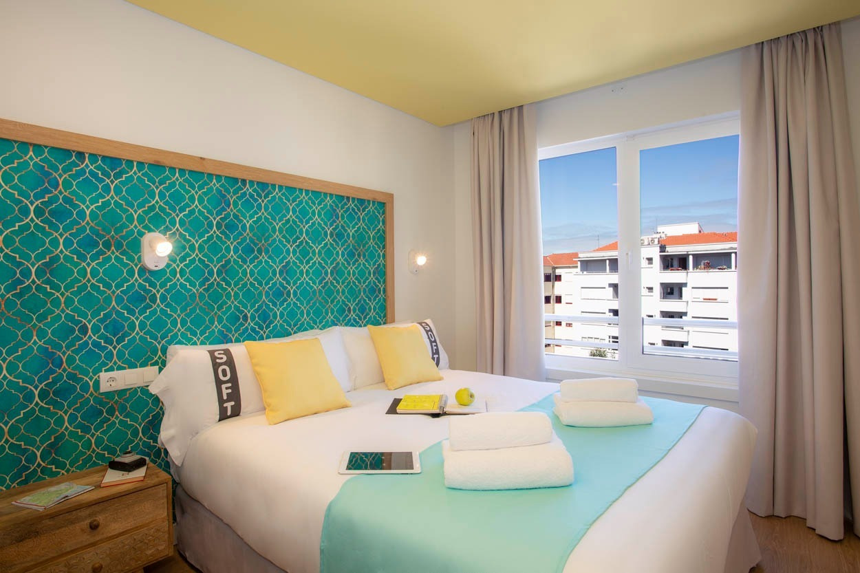 Camera d'hotel moderna con letto king, testata colorata e vista sulla città. Casual Raízes Porto - Boutique hotel vicino a Santa Catarina.