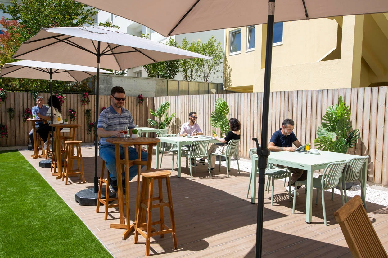 Terrazza esterna di Casual Raízes Porto - Boutique hotel, con tavoli e sedie tra ombrelloni.