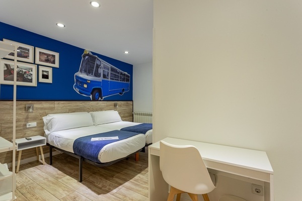 a bedroom with two beds and a blue bus on the wall