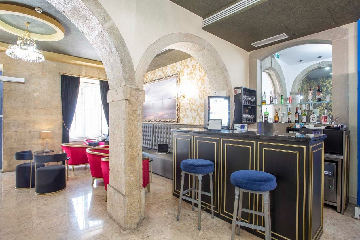 Bar-Bereich im Casual Belle Époque Boutique-Hotel in Lissabon mit roten Sesseln und Barhockern.