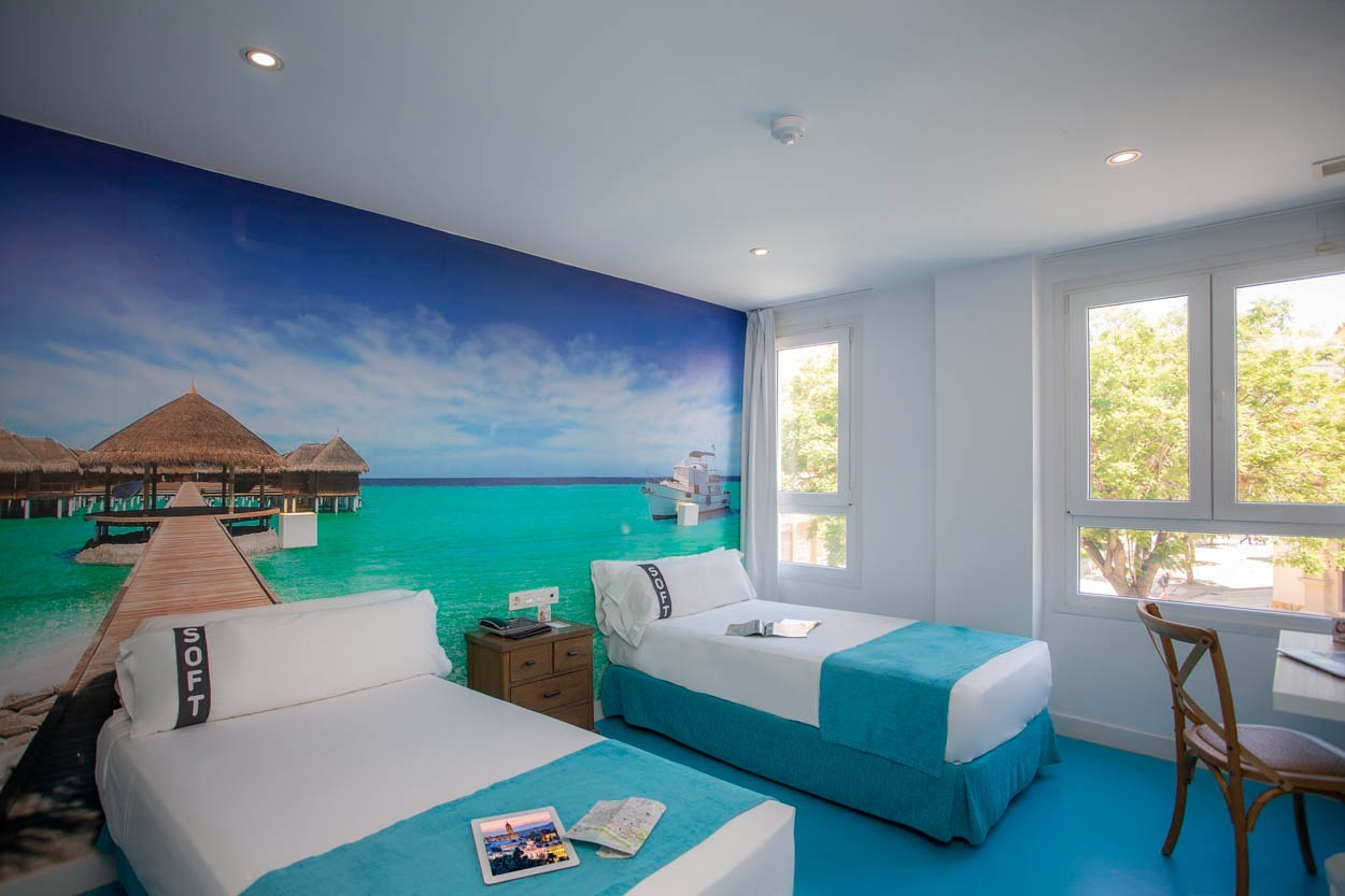 Zwei Betten in einem hellen Hotelzimmer mit tropischem Wandbild, Casual del Mar Málaga