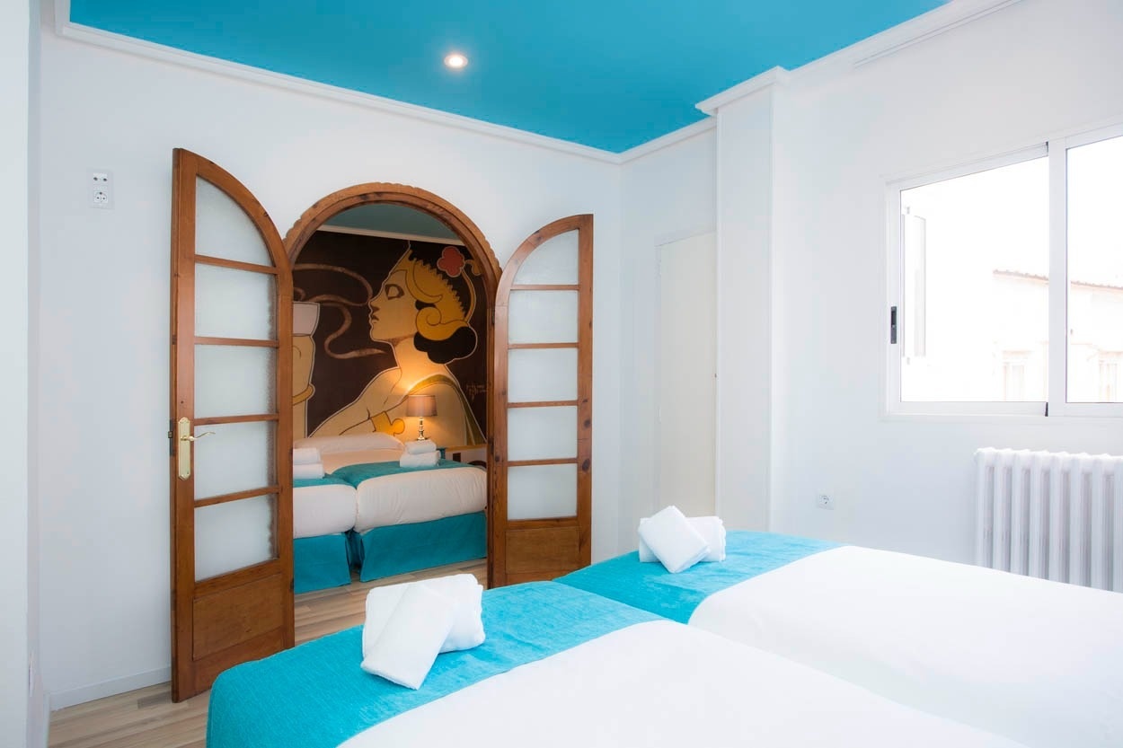 Habitación doble con mural Art Decó y camas gemelas en Casual Vintage Valencia, tu hotel céntrico cerca del Ayuntamiento.