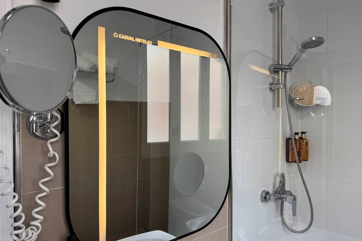 Modernes Badezimmer im Casual Hoteles Madrid mit beleuchtetem Spiegel und Dusche.
