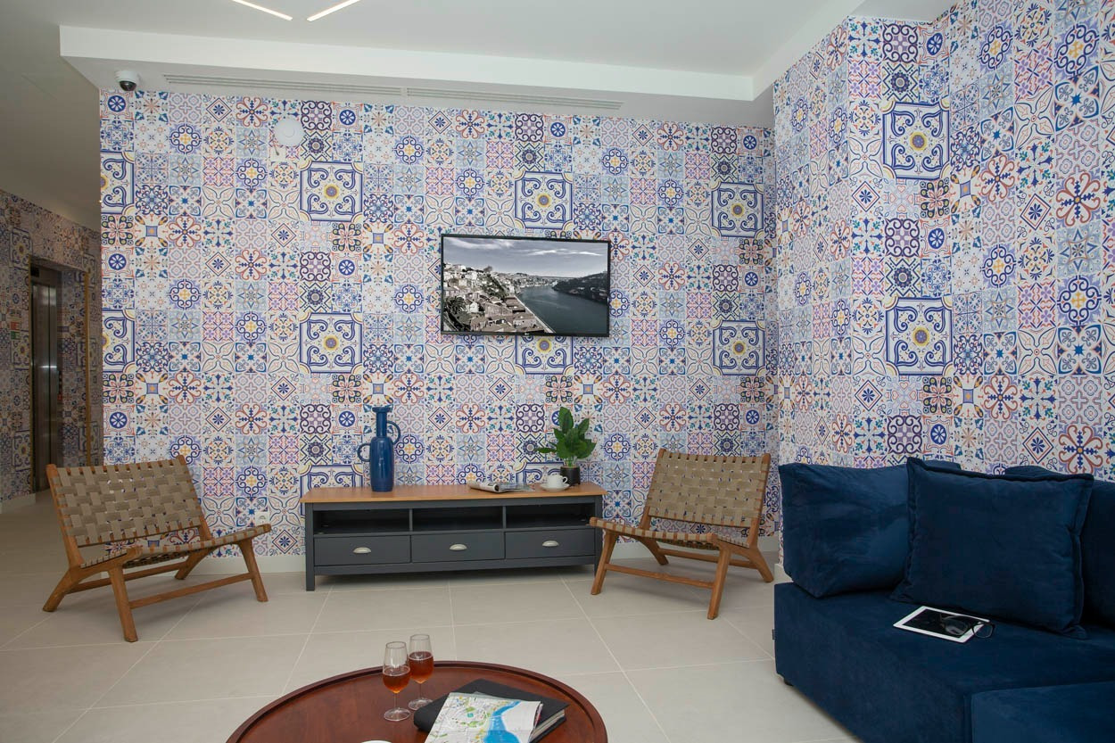 Soggiorno moderno al Casual Raízes Porto, con divano blu, sedie in legno e pareti decorate, hotel vicino a Santa Catarina.