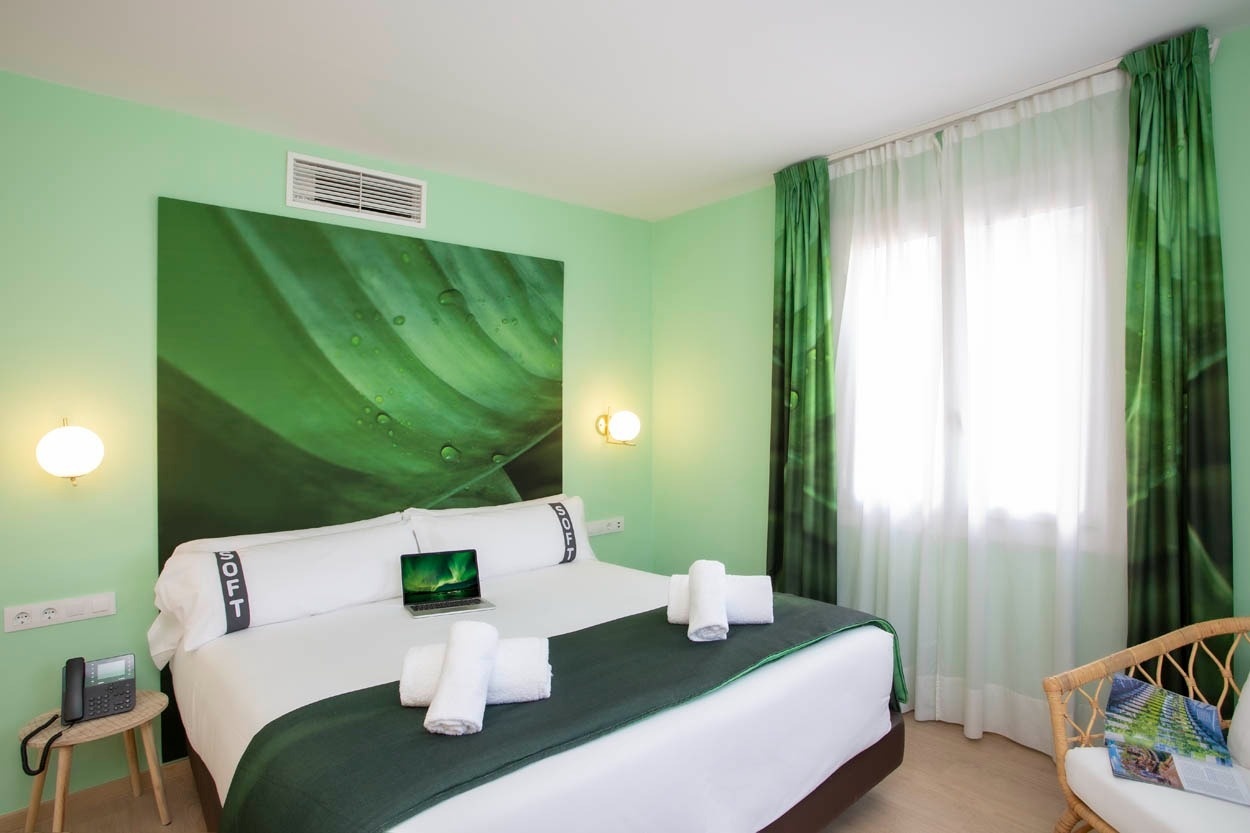 Moderne hotelkamer met groen thema en uitzicht op de stad. Casual Colours Barcelona - nabij Sants, Barcelona.