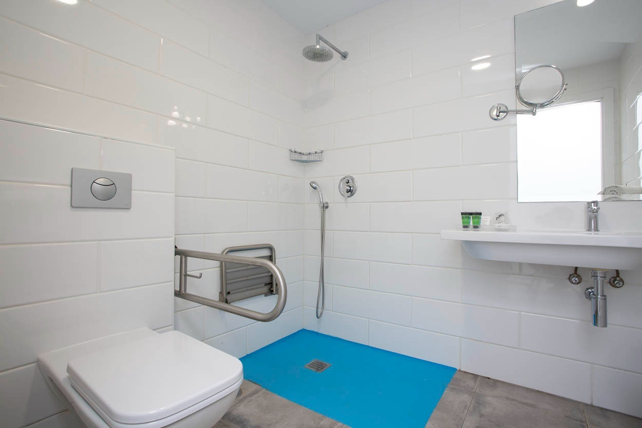 Barrierefreies Badezimmer im Casual del Mar Málaga: Dusche, WC mit Haltegriff und Waschbecken.