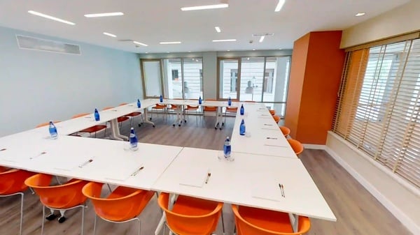 een vergaderruimte met witte tafels en oranje stoelen
