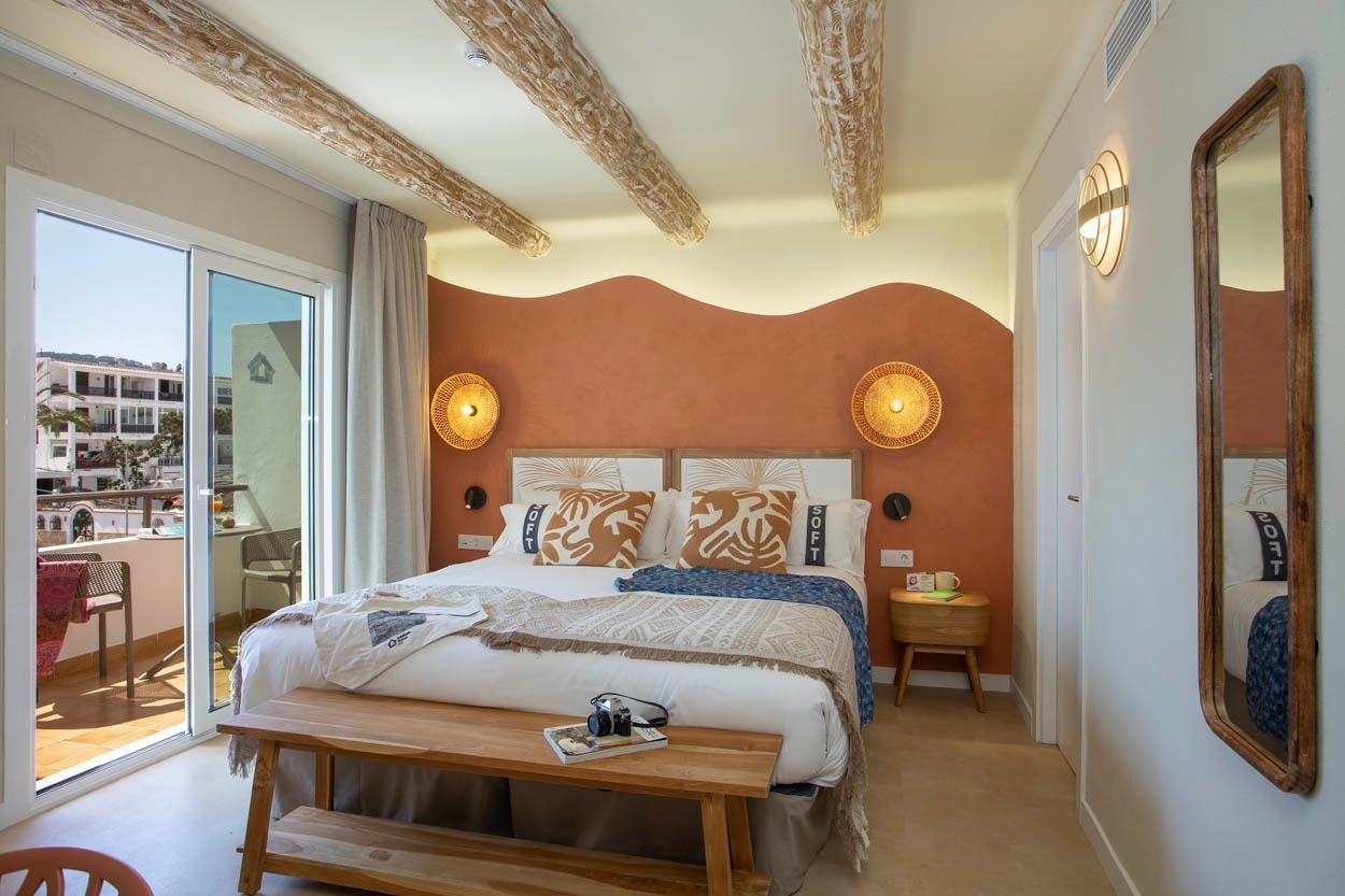 Chambre confortable Casual Bahía Ibiza, décorée avec des poutres en bois et des couleurs terre, vue sur la mer.