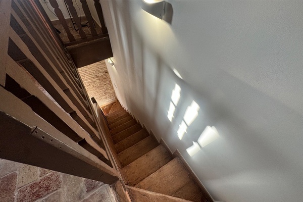 un escalier en bois avec une lumière qui brille sur le mur