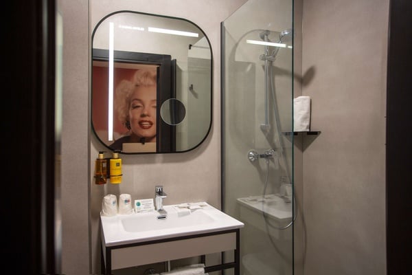un baño con una pintura de marilyn monroe en el espejo