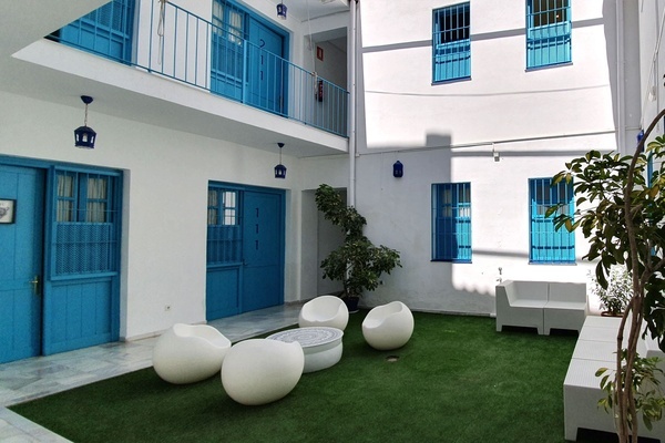 a courtyard with blue doors and white chairs