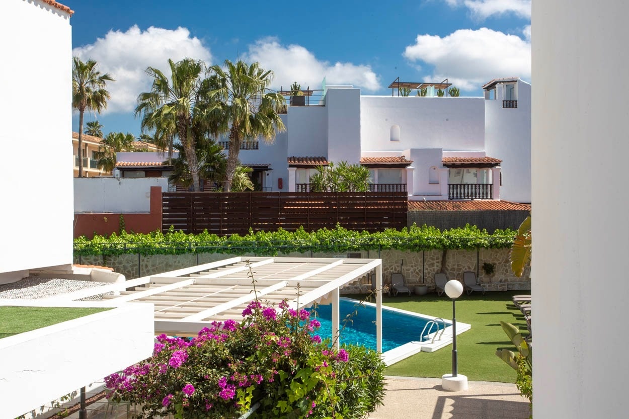 Piscine ensoleillée et palmiers devant le Casual Bahía Ibiza, hôtel de charme proche de la plage.