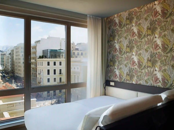 een hotelkamer met een bed en een groot raam