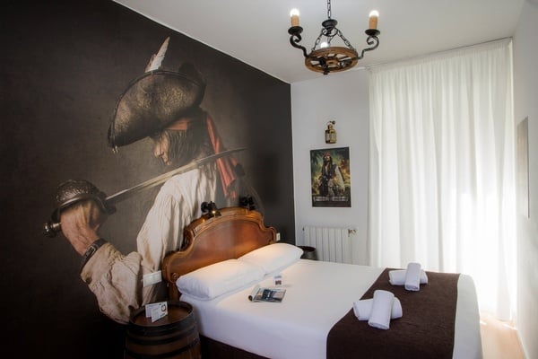 una habitación con una cama y una pintura de un pirata en la pared