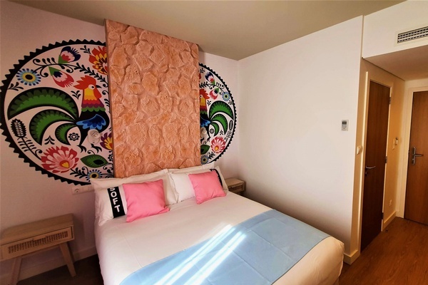 a bed in a hotel room with a rooster painting on the wall