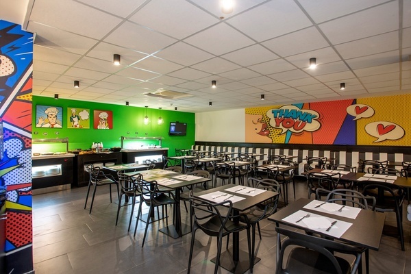 un restaurante con mesas y sillas y un mural que dice 