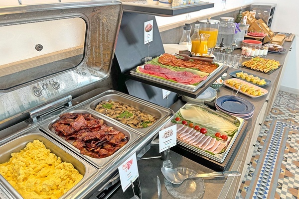 uma mesa de buffet cheia de comida incluindo bacon e ovos mexidos