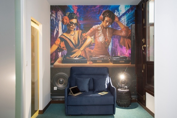 uma cadeira azul está em frente a uma pintura de uma mulher dj
