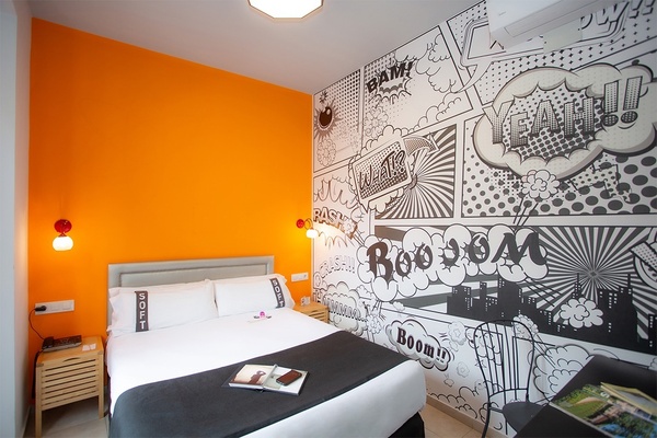une chambre avec un lit et un mur orange avec des illustrations de bande dessinée