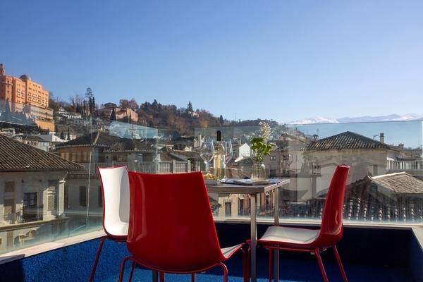 uma mesa e cadeiras vermelhas em uma varanda com vista para uma cidade
