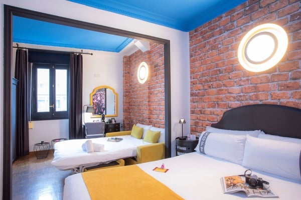 een hotelkamer met een bed en een bank en een muur met bakstenen