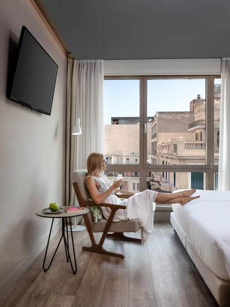 een vrouw zit in een stoel in een hotelkamer en kijkt naar haar telefoon