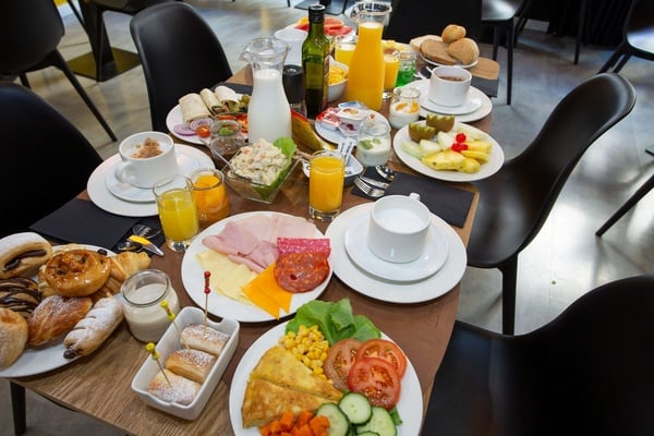 a table topped with plates of food and drinks including orange juice