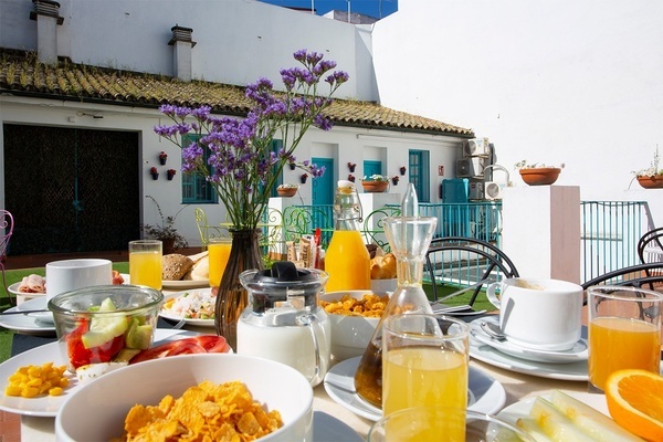 a table full of food and drinks with purple flowers in the background