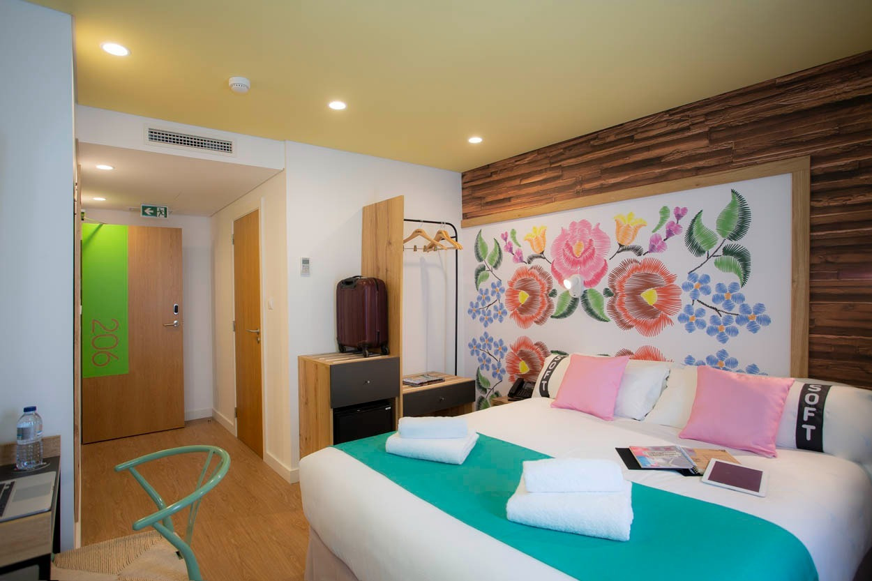 Camera doppia con letto matrimoniale, decorazione floreale e minibar, hotel Casual Raízes Porto vicino a Santa Catarina.