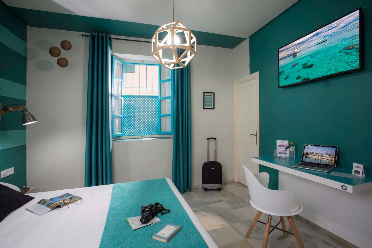 Modernes Hotelzimmer mit Schreibtisch, Laptop und Stadtblick im Casual de las Letras Sevilla – Hotel mit literarischem Thema in Sevilla | Casual Hoteles