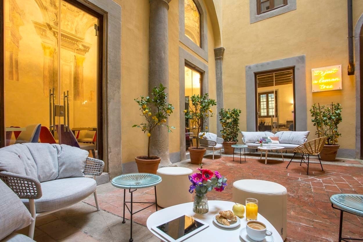 Gemütlicher Innenhof des Casual Rinascimento Firenze, mit Sitzgelegenheiten im Freien und Zitrusbäumen. Zentrales Hotel in Florenz.