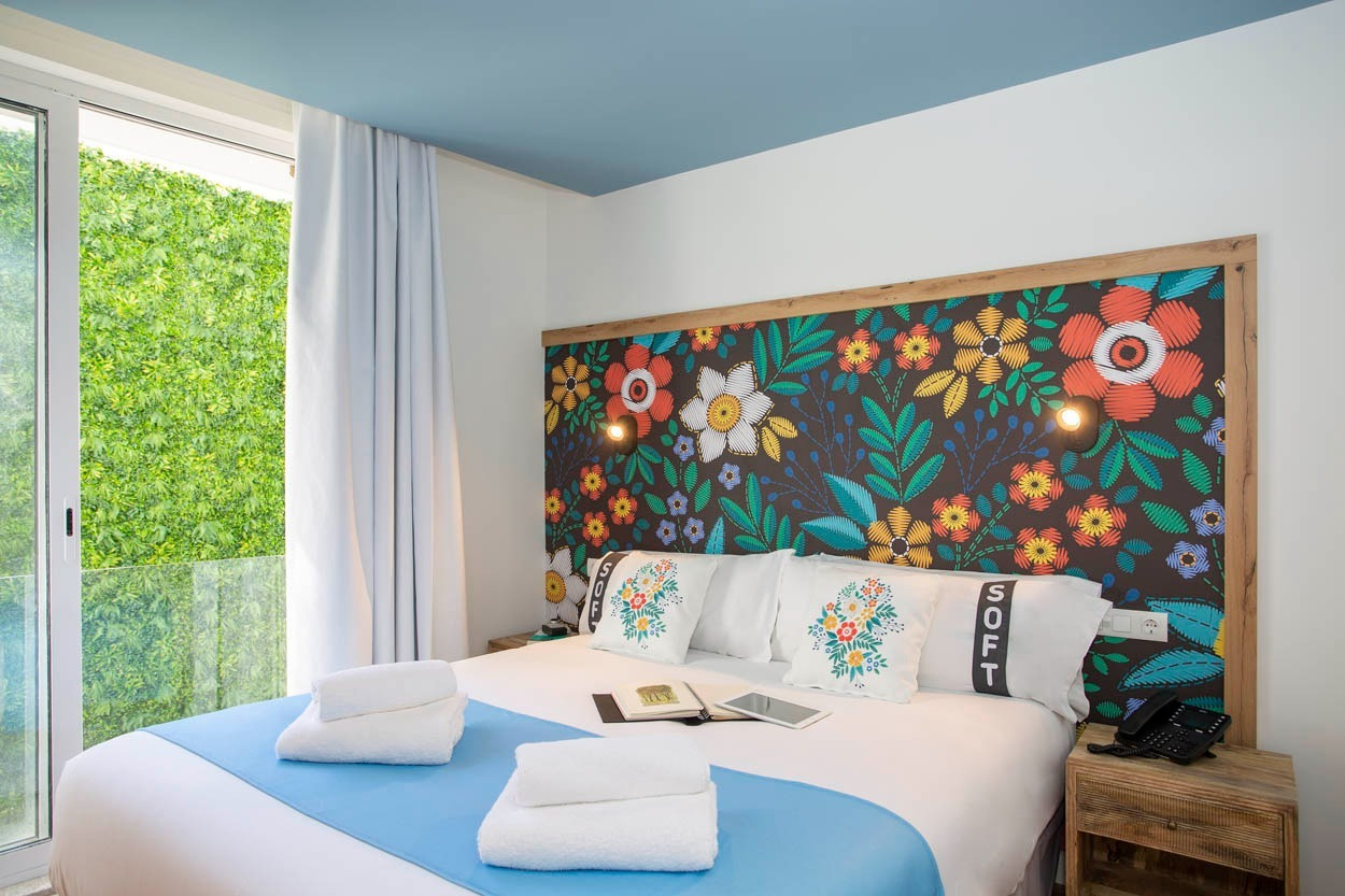 Camera d'albergo Casual Raízes Porto con parete floreale vibrante e vista sul verde.