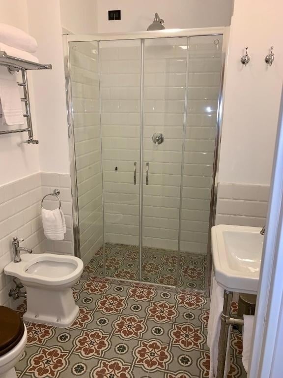 a bathroom with a toilet a bidet a sink and a walk in shower