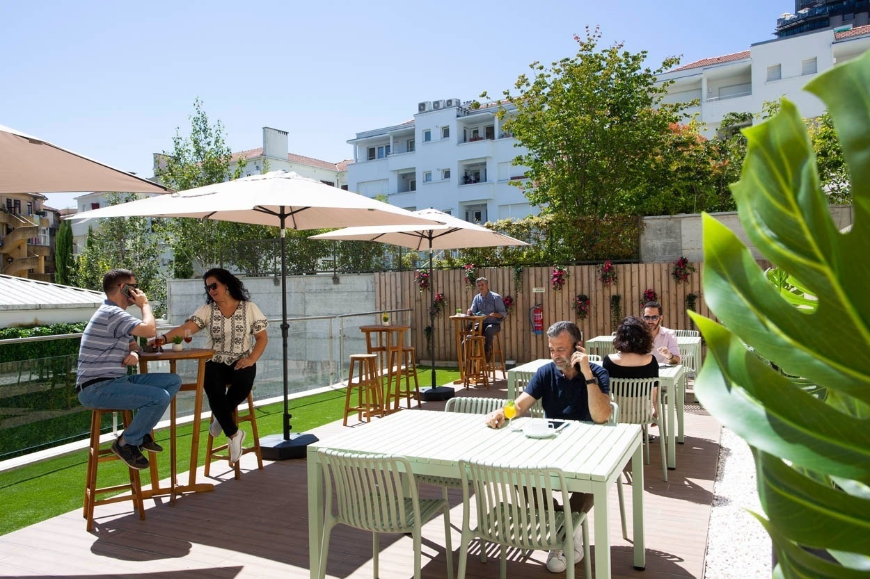 Terrazza casual del Casual Raízes Porto con tavoli e ombrelloni, ideale per rilassarsi.