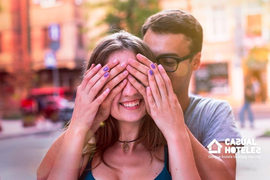 a man is covering a woman 's eyes with his hands