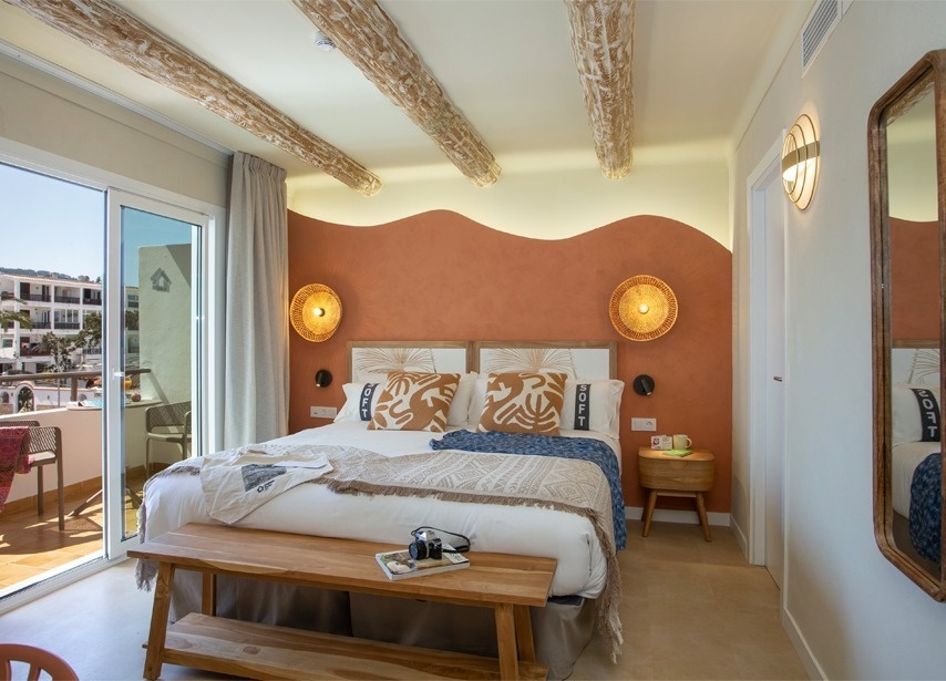 uma cama com um edredom branco e almofadas roxas