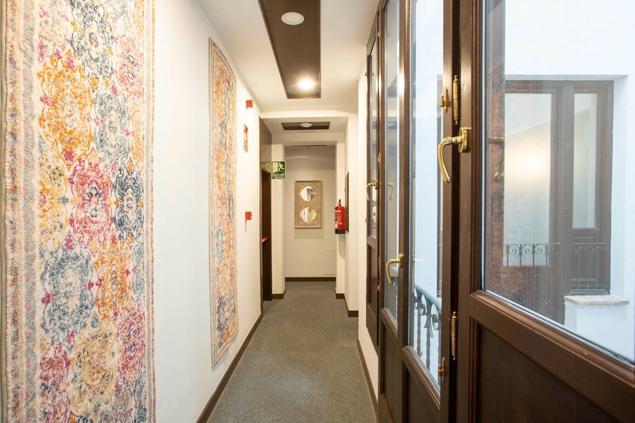 Pasillo del Casual Ilbira Granada: alfombras y puertas de madera con estilo. Hotel boutique céntrico.