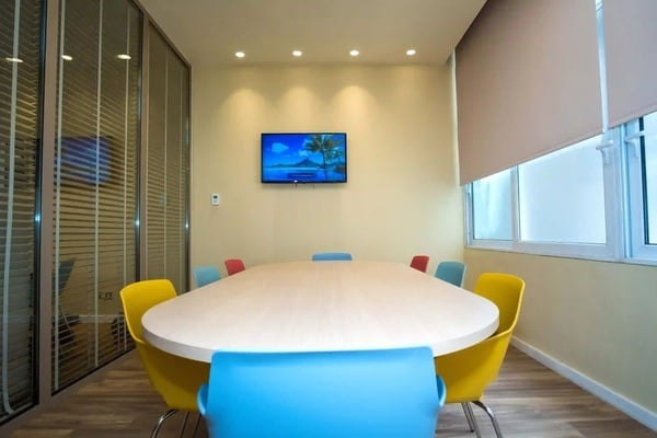 een vergaderruimte met een ovale tafel en kleurrijke stoelen