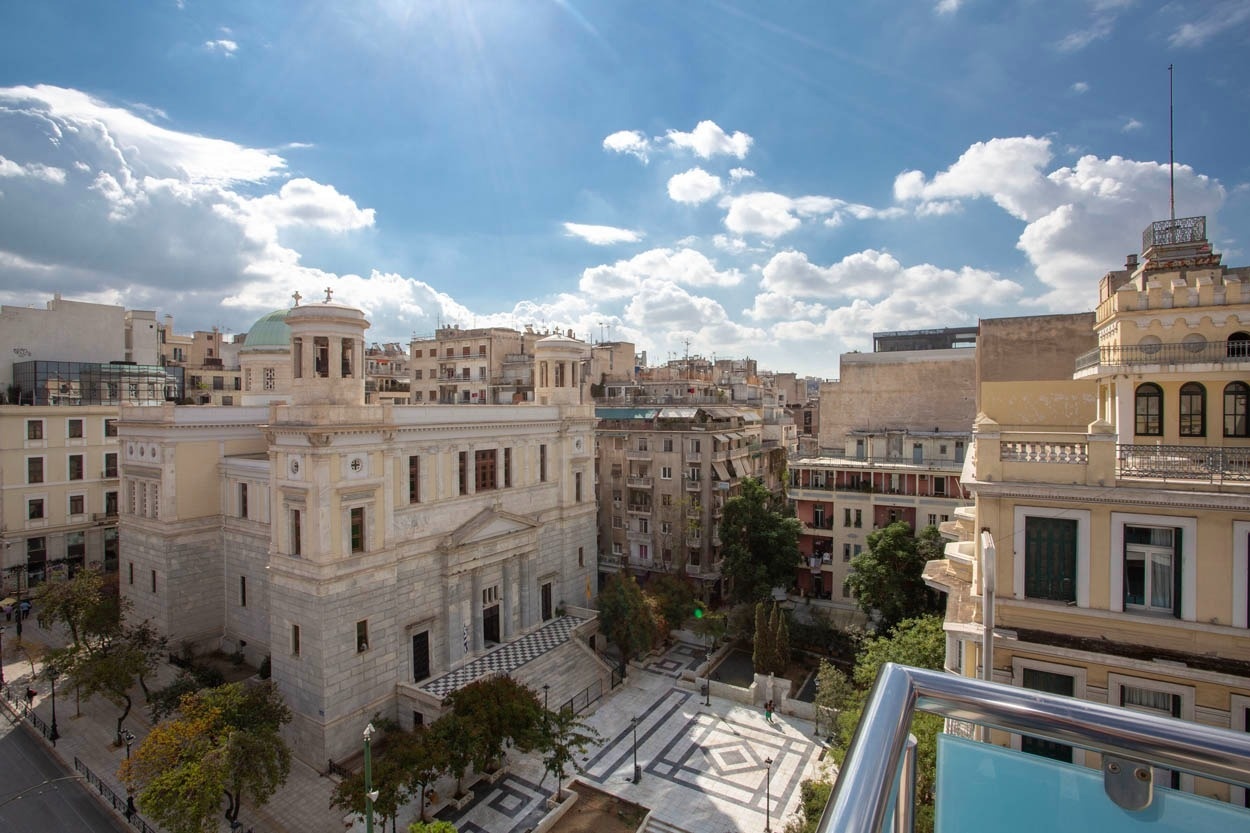 Casual Kubic Athens: Sonnige Aussicht auf historische Gebäude, ideal für Ihren Städtetrip.