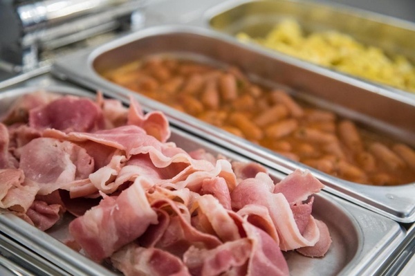 a tray of bacon next to a tray of sausages