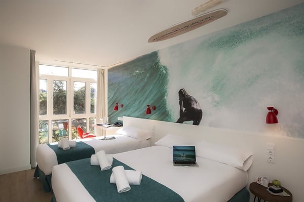 um quarto com duas camas e uma prancha de surf na parede