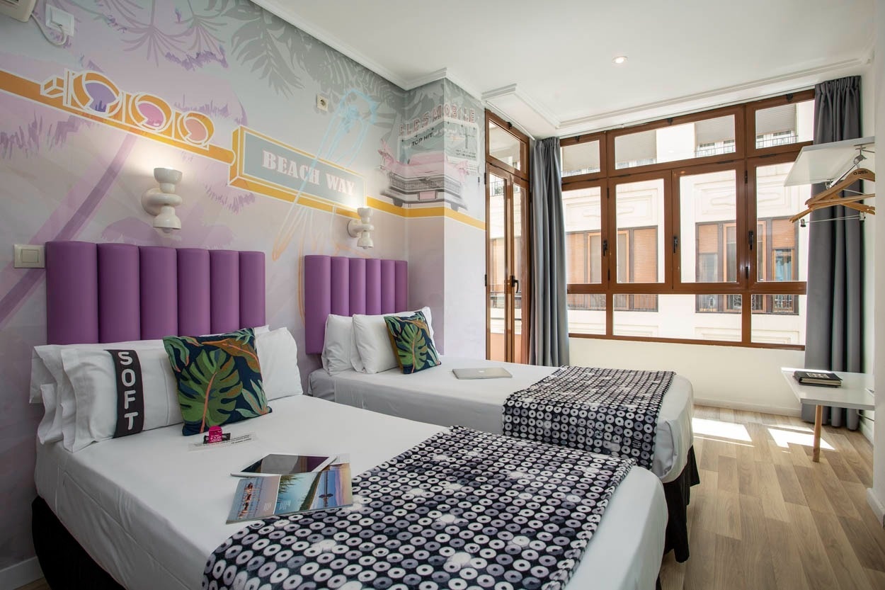 Habitación Casual Vintage Valencia con dos camas, mural playero y ventanas amplias.