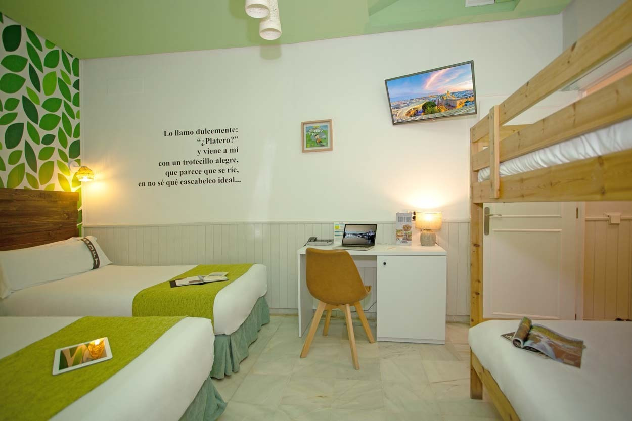 Gemütliches Zimmer im Casual de las Letras Sevilla: Betten, Schreibtisch & Bunk Bett – Hotel mit literarischem Thema.
