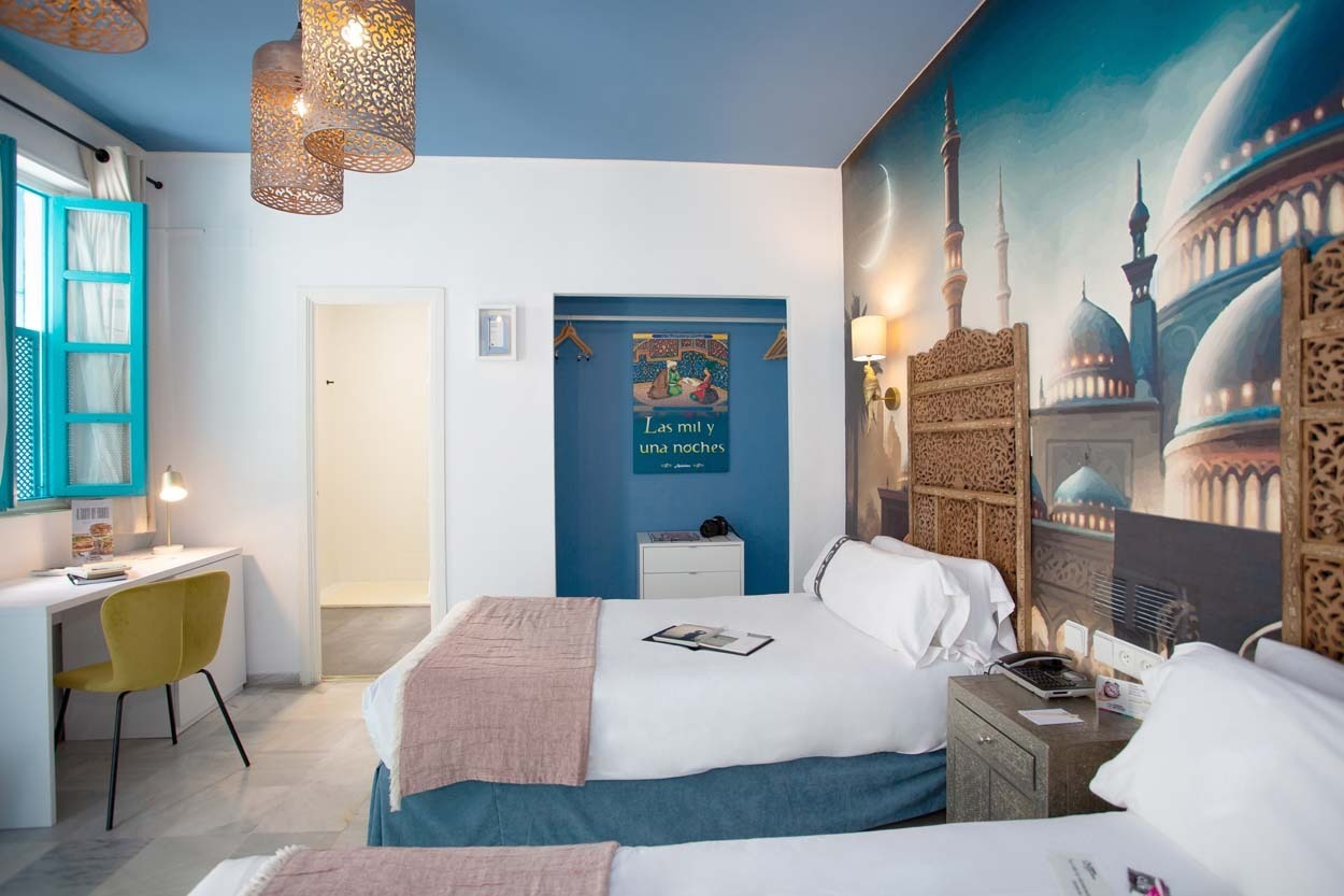 Geräumiges Zimmer im Casual de las Letras Sevilla mit Wandgemälde im Stil von Tausendundeiner Nacht und zwei Betten.