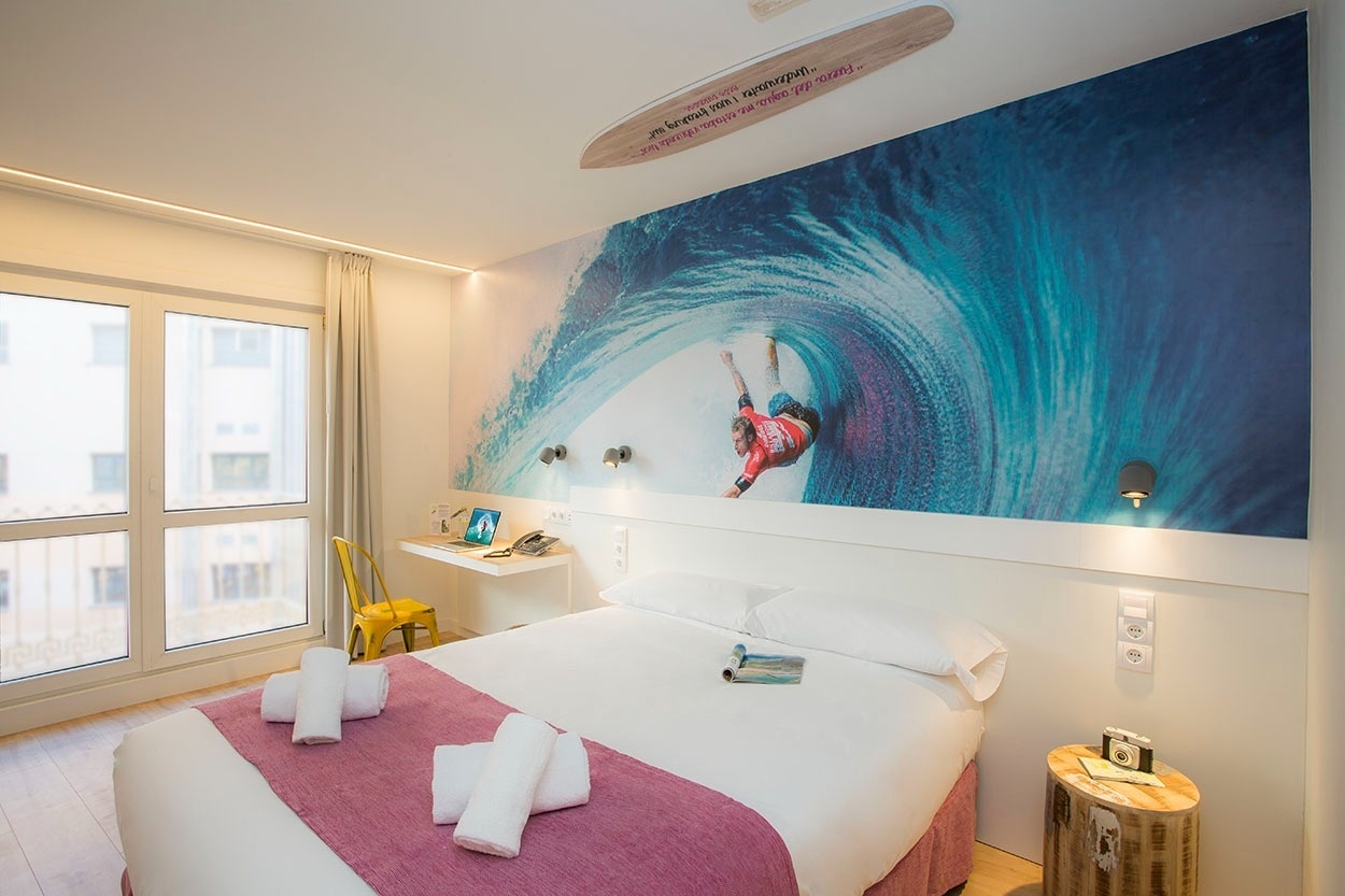 Modernes Hotelzimmer mit Wellen-Wandbild, ideal für Surfer. Casual de las Olas San Sebastián.