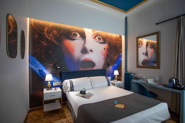 een slaapkamer met een bed en een schilderij van een vrouw op de muur