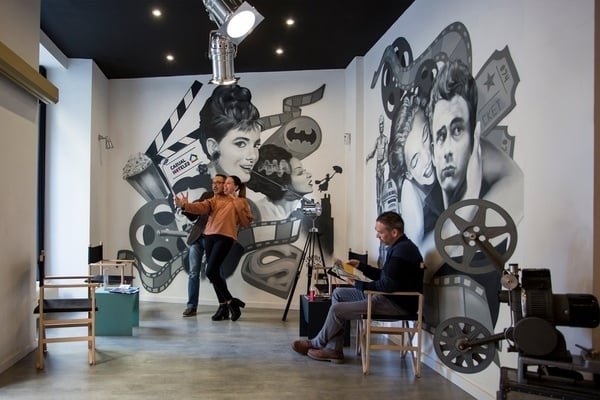 un hombre y una mujer posan para una foto frente a un mural de películas